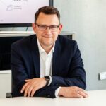 Man in suit and glasses sits at table